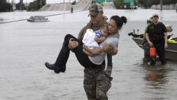 CORRECTS FROM CONNIE TO CATHERINE - Houston Police SWAT officer Daryl Hudeck carries Catherine Pham and her 13-month-old son Aiden after rescuing them from their home surrounded by floodwaters from Tropical Storm Harvey Sunday, Aug. 27, 2017, in Houston. The remnants of Hurricane Harvey sent devastating floods pouring into Houston Sunday as rising water chased thousands of people to rooftops or higher ground. (AP Photo/David J. Phillip)