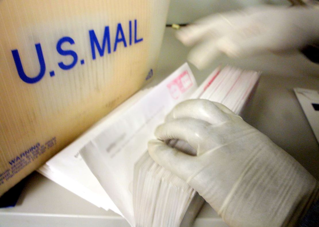 A corporate mailroom employee in New York City uses gloves while sifting through letters in October 2001.