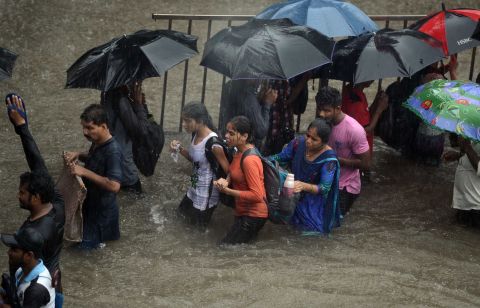 Heavy rain showers brought Mumbai to a standstill. Pedestrians had to walk through flooded streets, while dozens of flights and local train services were canceled.