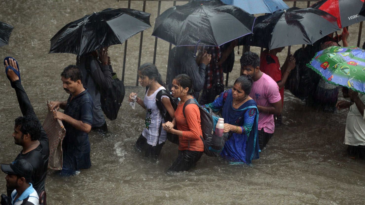 People walk along a flooded street during heavy rain in Mumbai on Tuesday.