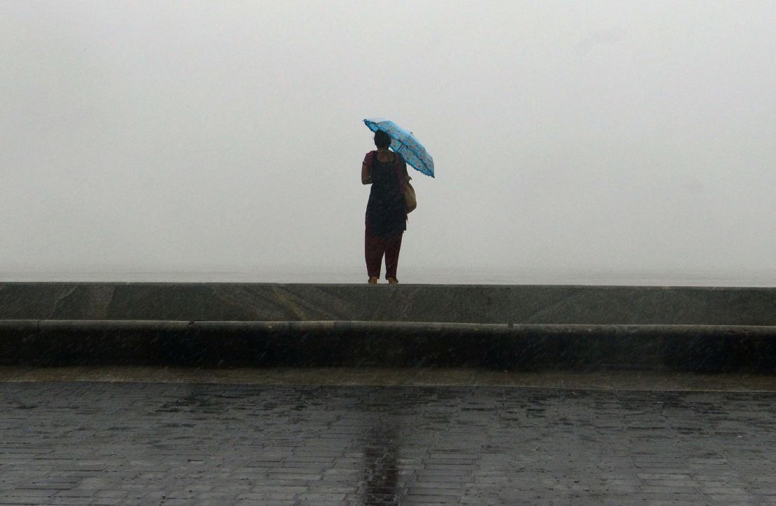 Heavy rainfall caused chaos in the coastal city (above). A woman is seen (below) on the sea front during the heavy rain showers on Tuesday.