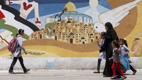 Palestinians walk past a mural in Gaza in 2014 featuring Handala, Naji al-Ali's most famous character, holding the key to the city of Jerusalem.
