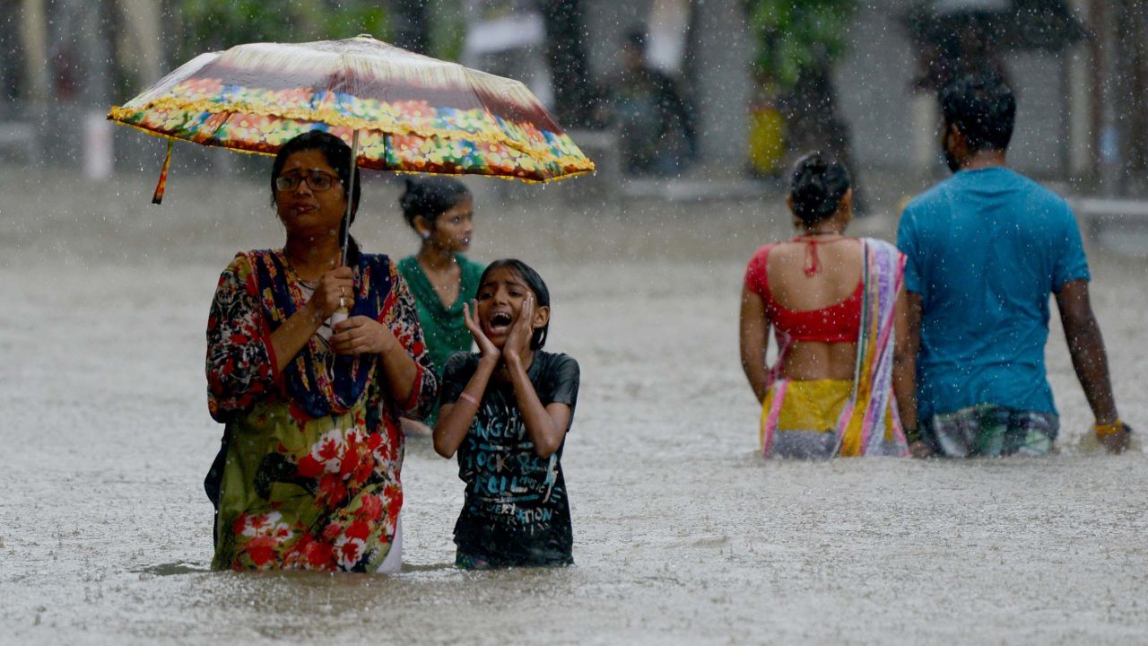 People wade through a flooded street during heavy rain showers in Mumbai on August 29, 2017.