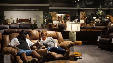 David and Maria Parks sit on a couch in the Gallery Furniture showroom, watching local news coverage of the floods.