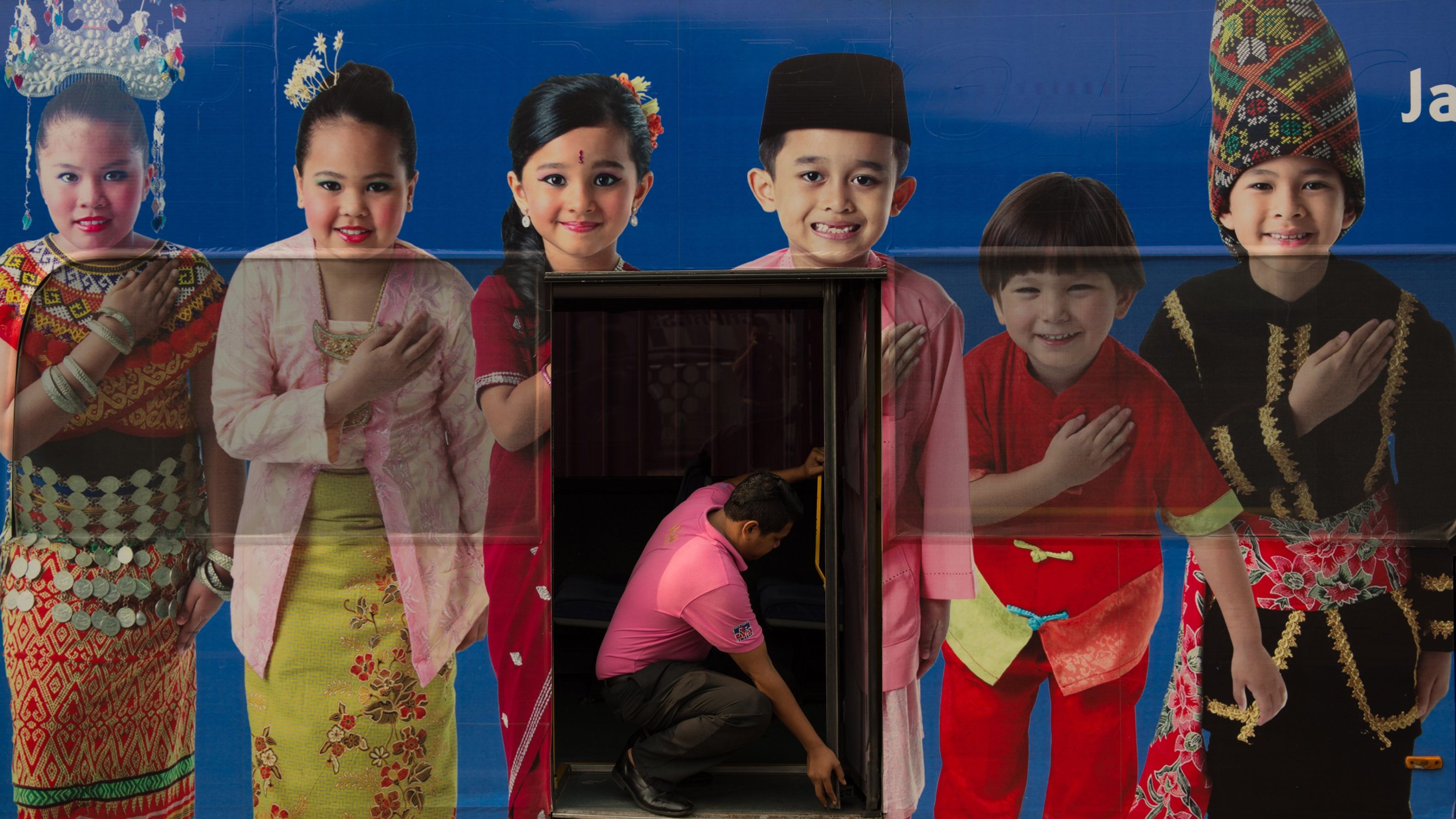 A man opens a bus door through an advertisement showing the Malaysia ethnic communities with traditional dress in Kuala Lumpur, September 25, 2013. 