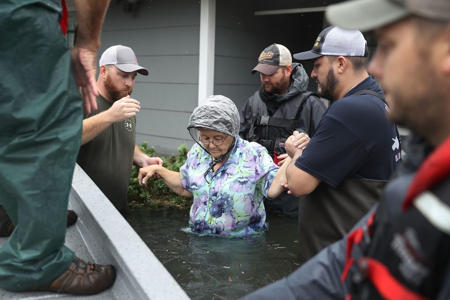 Volunteer rescue workers help a woman from her flooded home in Port Arthur, Texas.