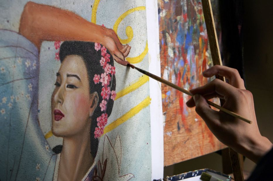 <strong>Paint the town: </strong>An artist at work inside a studio at the Dafen Oil Painting Village. As many as 8,000 artists live in the 1.5-square-mile village specializing in the creation and imitation of famous paintings. 