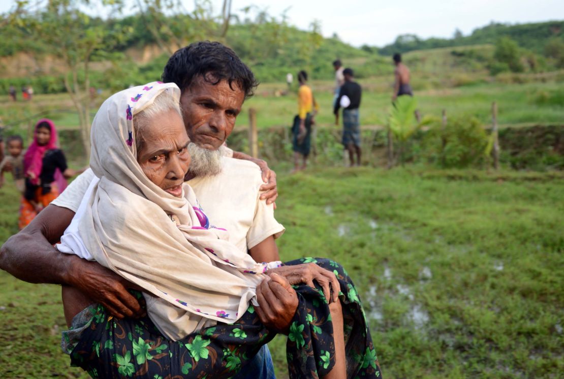 A Rohingya man carries his mother in Ukhiya, Bangladesh, after crossing the border from Myanmar.