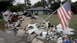 Tattered flags fly over a pile of water-soaked items as people clean up in a flood ravaged neighborhood Thursday, Aug. 31, 2017, in Houston. The city continues to recover from record flooding caused by Harvey. (AP Photo/Charlie Riedel)