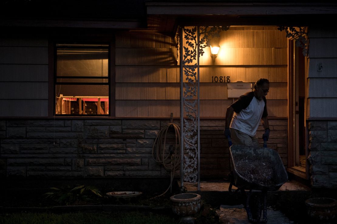 A man brings a wheelbarrow back to his flooded house in Houston to salvage items.