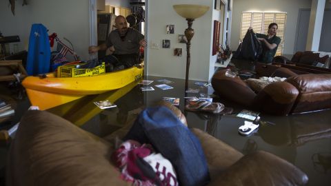 Larry Koser Jr. and his son Matthew look for important papers and heirlooms inside a flooded home in Houston.