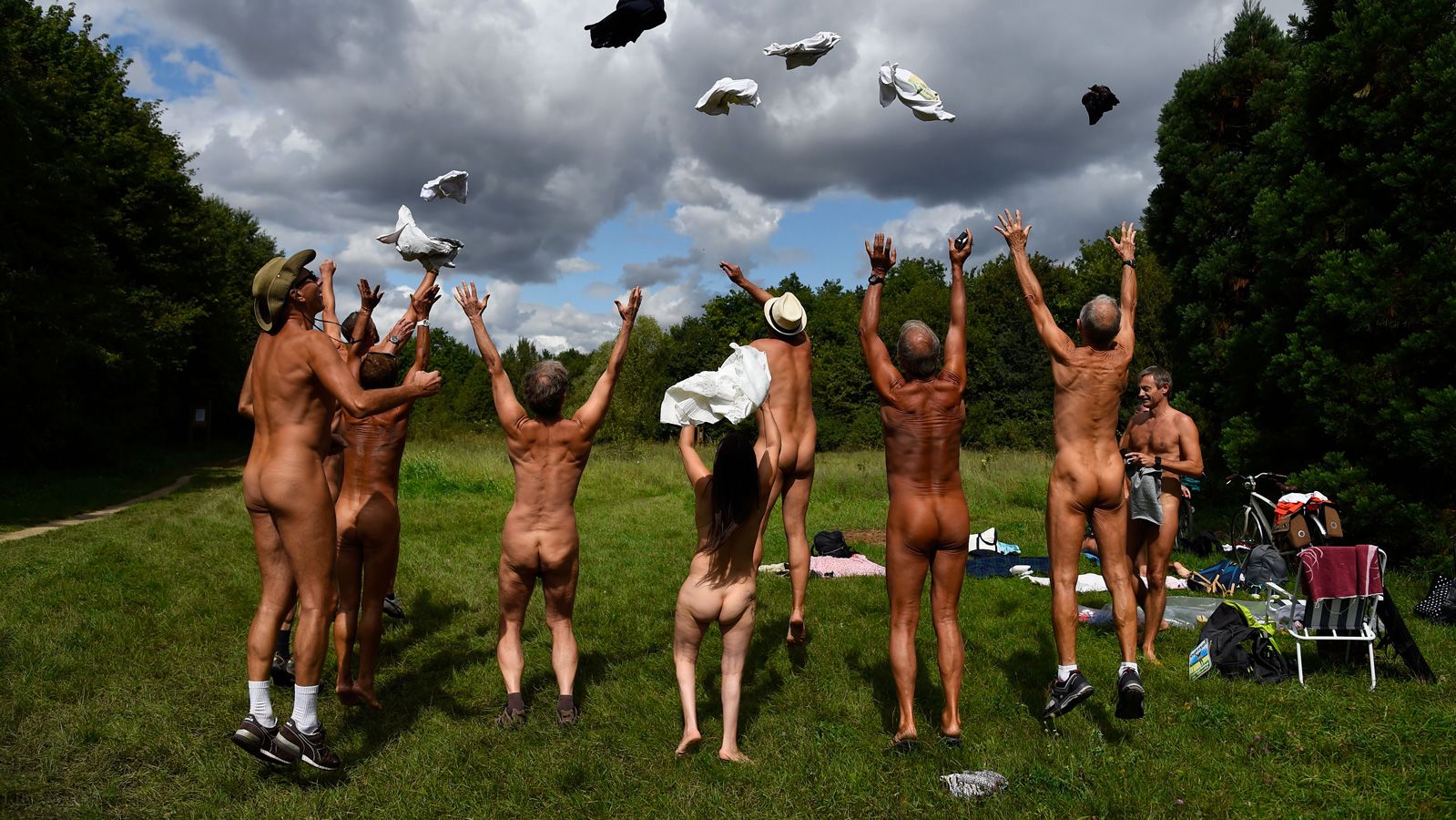 Naked people throw their clothes up in the air at a newly opened space for naturists at the Bois de Vincennes park in Paris on August 31, 2017. The space will be open daily until October 15th. / AFP PHOTO / Bertrand GUAY (Photo credit should read BERTRAND GUAY/AFP/Getty Images)