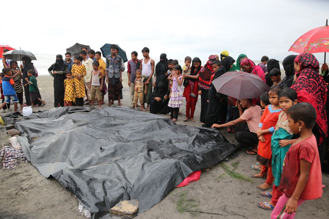 People gather around covered dead bodies of Rohingya children who died after a boat carrying Rohingya people capsized.