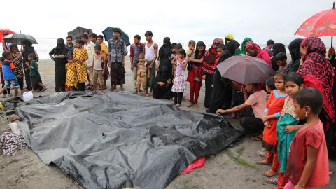People gather around covered dead bodies of Rohingya children who died after a boat carrying Rohingya people capsized.