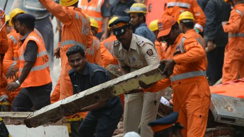 Rescue workers and a policeman help clear debris as they look for survivors.