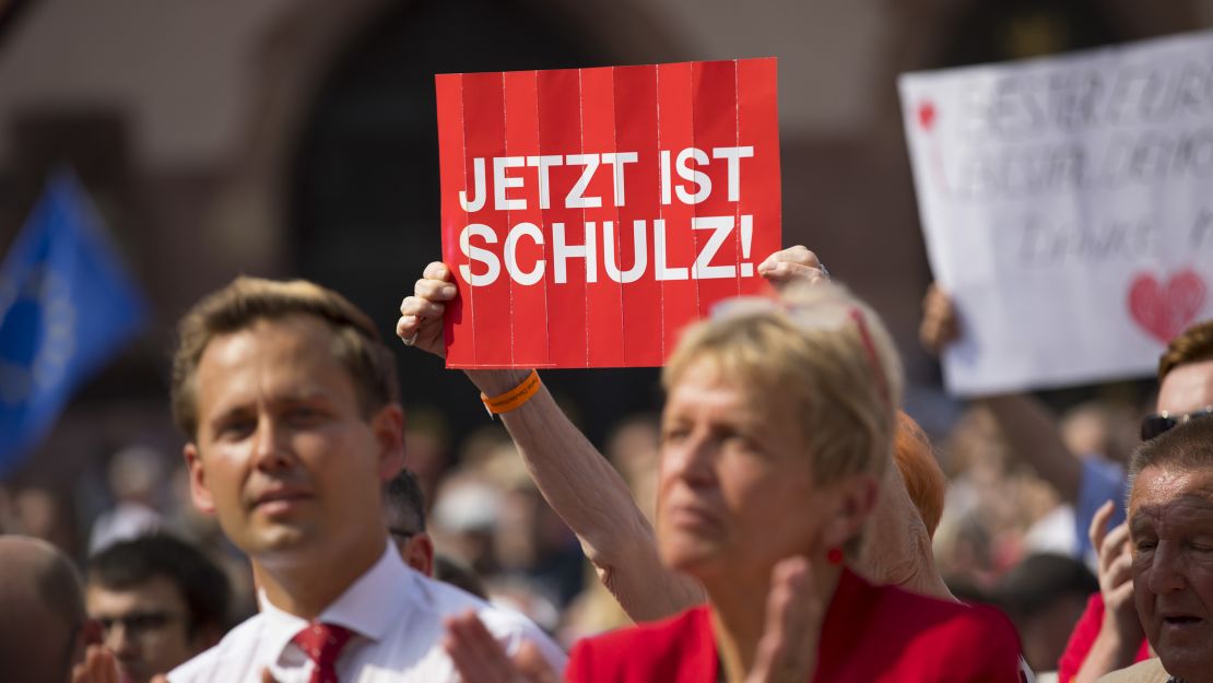 An SPD supporter holds up a "Now Is Schulz" poster at a campaign rally.