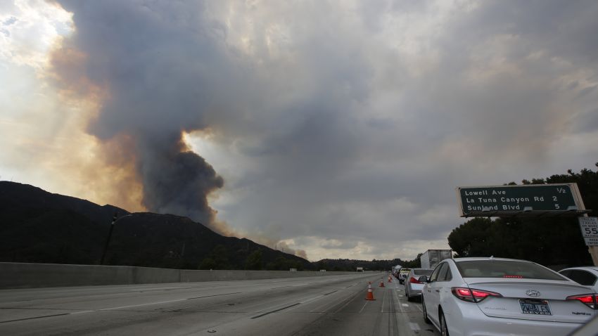 A plume of smoke is seen from the 210 Freeway as a brush fire burns in the Verdugo Mountains in the Sun Valley neighborhood of Los Angeles. (AP Photo/Damian Dovarganes)