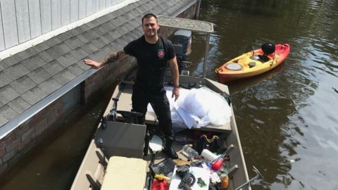Kyle Parry outside his flooded home, with his fiancee's wedding dress safely aboard his boat.