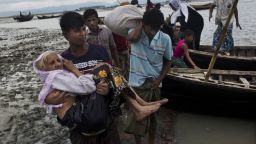 A Rohingya ethnic minority from Myanmar carries an elderly woman as they alight from a local boat on which they crossed a river, after crossing over to the Bangladesh side of the border near Cox's Bazar's Dakhinpara area, Saturday, Sept. 2, 2017. Tens of thousands more people have crossed by boat and on foot into Bangladesh in the last 24 hours as they flee violence in western Myanmar, the UNHCR said Saturday. (AP Photo/Bernat Armangue)