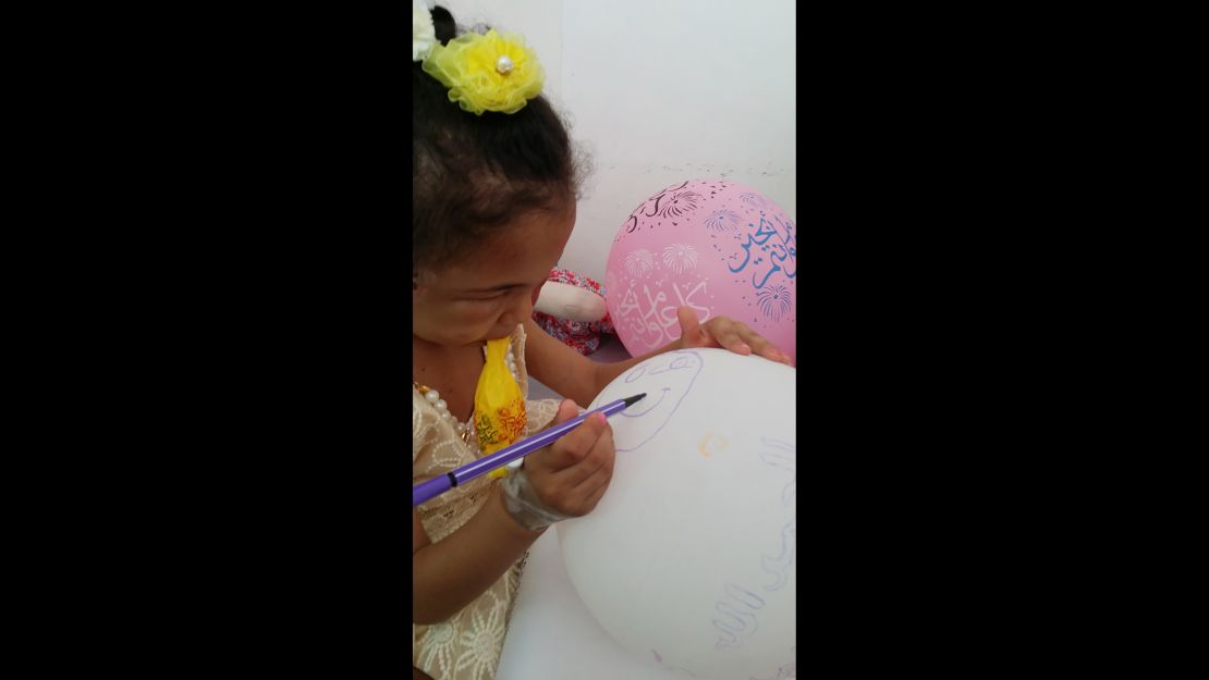Buthaina draws on a balloon brought to her by one of her visitors. 