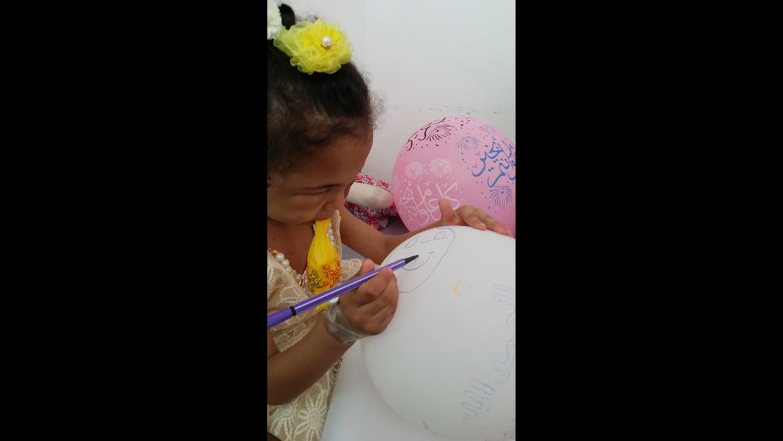 Buthaina draws on a balloon brought to her by one of her visitors.