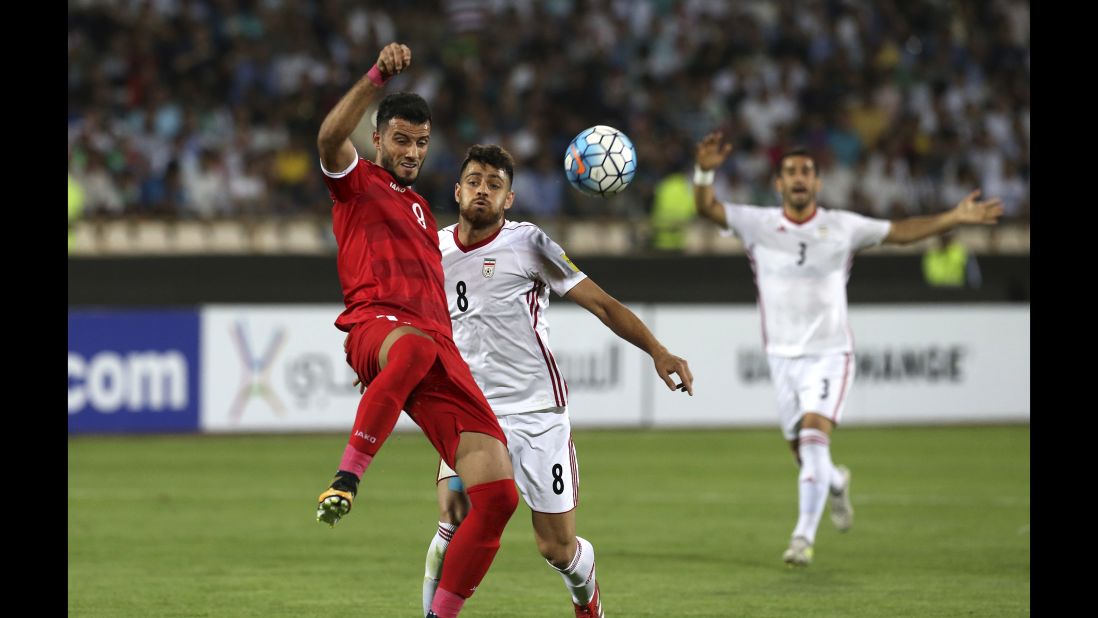 Syria's Omar Al Somah, left, fends off Iran's Morteza Pouraliganji during Tuesday's qualifier. Al Somah scored the game-tying goal late in stoppage time.