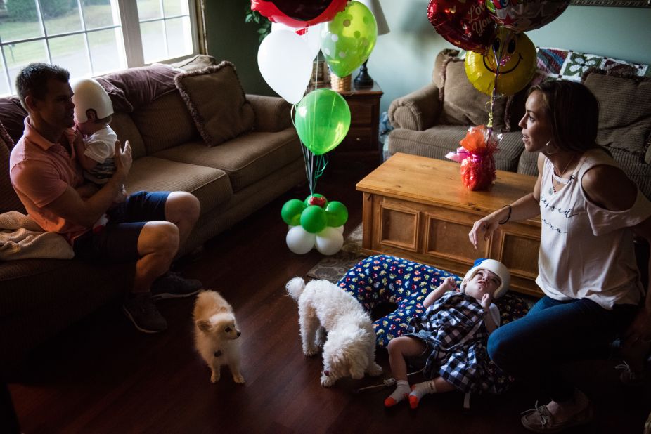 Christian McDonald holds his son Anias as Nicole McDonald checks on Jadon at home with the family dogs, Taz and Tyson.