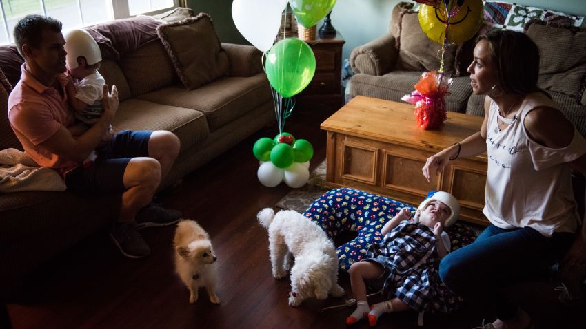 Christian McDonald holds his son Anias as Nicole McDonald checks on Jadon at home with the family dogs, Taz and Tyson.