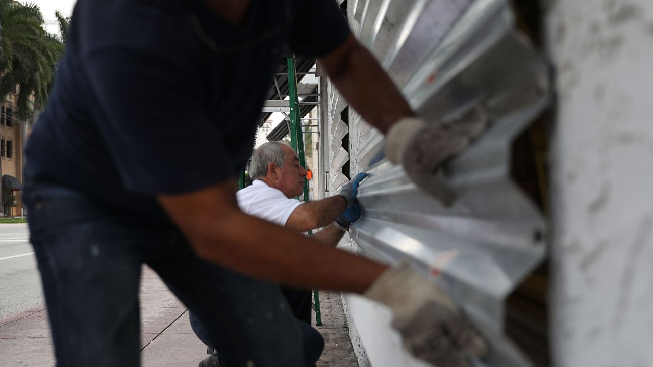 Winston Mora, left, and Gus Sousa put hurricane shutters on a business Wednesday in Miami.