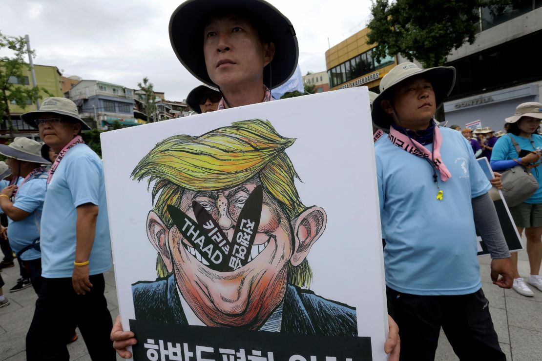 A protester holds a placard with an illustration of US President Donald Trump during a rally against THAAD near the US army base on August 14, 2017 in Seoul, South Korea.