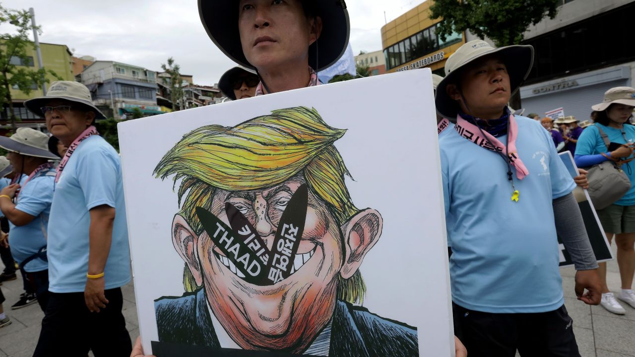 A protester holds a placard with an illustration of US President Donald Trump during a rally against THAAD near the US army base on August 14, 2017 in Seoul, South Korea.