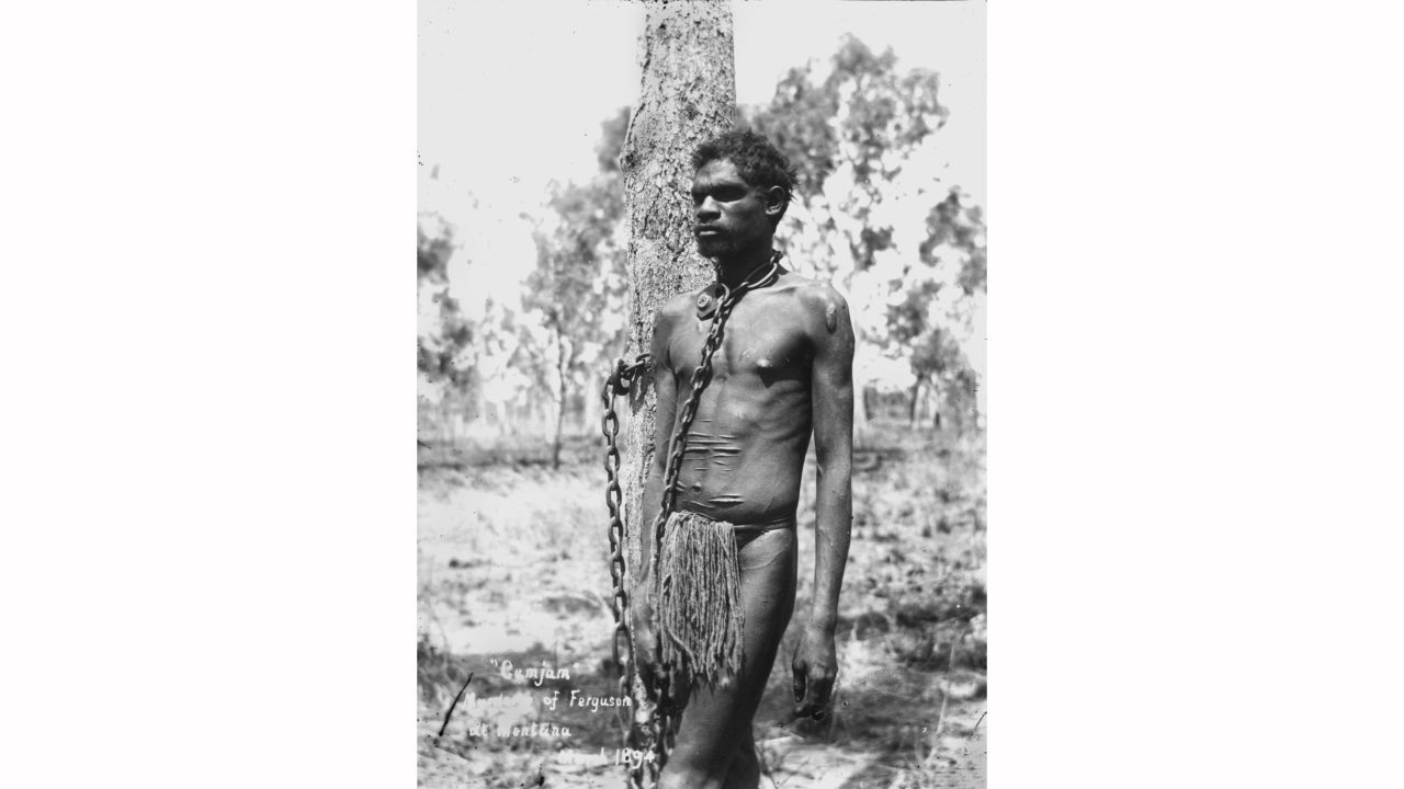An archival image shows the type of scene that inspired Semu's work. This image from 1894 shows an aboriginal man in chains after being arrested for murder in Mentana, Queensland.