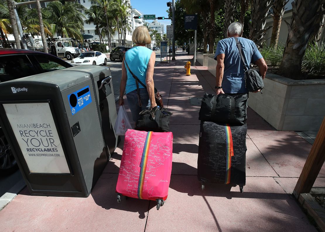 Tourist Bjorg Aasen and Arne Forsmo walk to catch a shuttle to a shelter on Friday in Miami Beach.