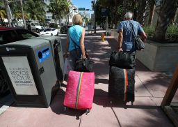 Tourist Bjorg Aasen and Arne Forsmo walk to catch a shuttle to a shelter as Miami Beach announced a mandatory evacuation.