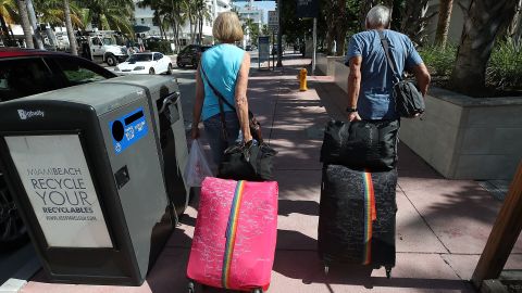 Tourist Bjorg Aasen and Arne Forsmo walk to catch a shuttle to a shelter as Miami Beach announced a mandatory evacuation.