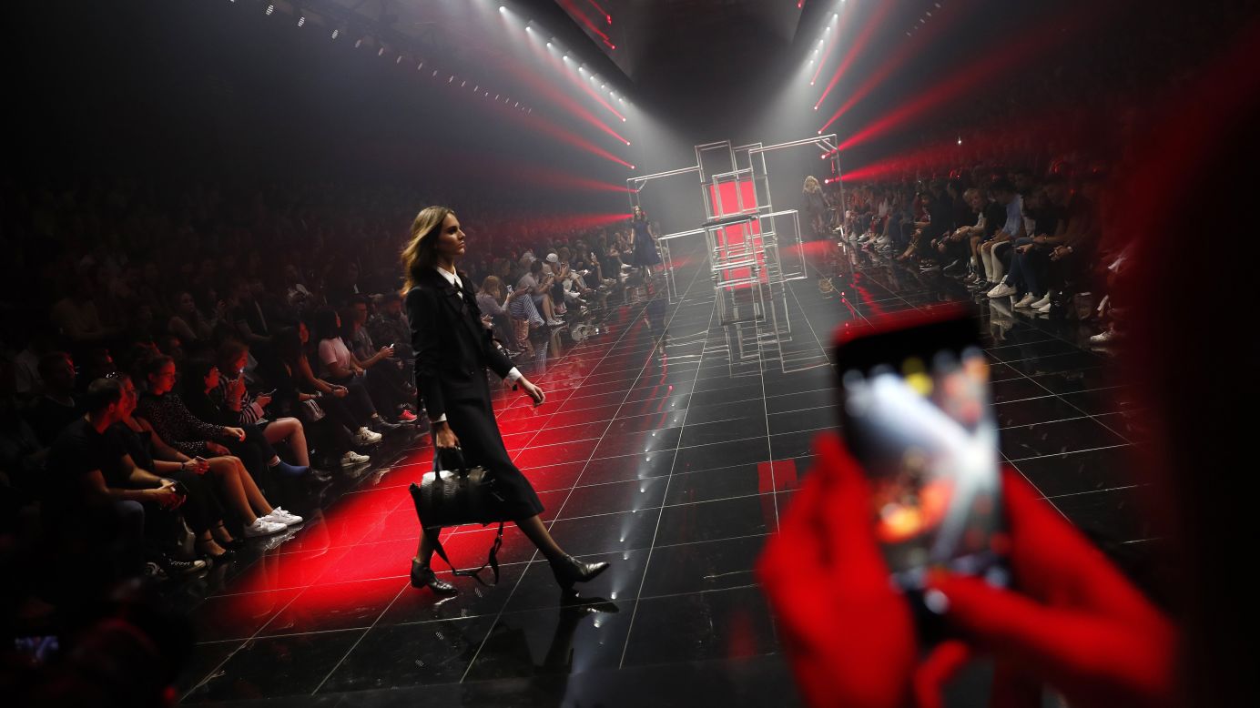 A woman uses her phone to take a photo of a model during a Hugo Boss fashion show in Berlin on Saturday, September 2.