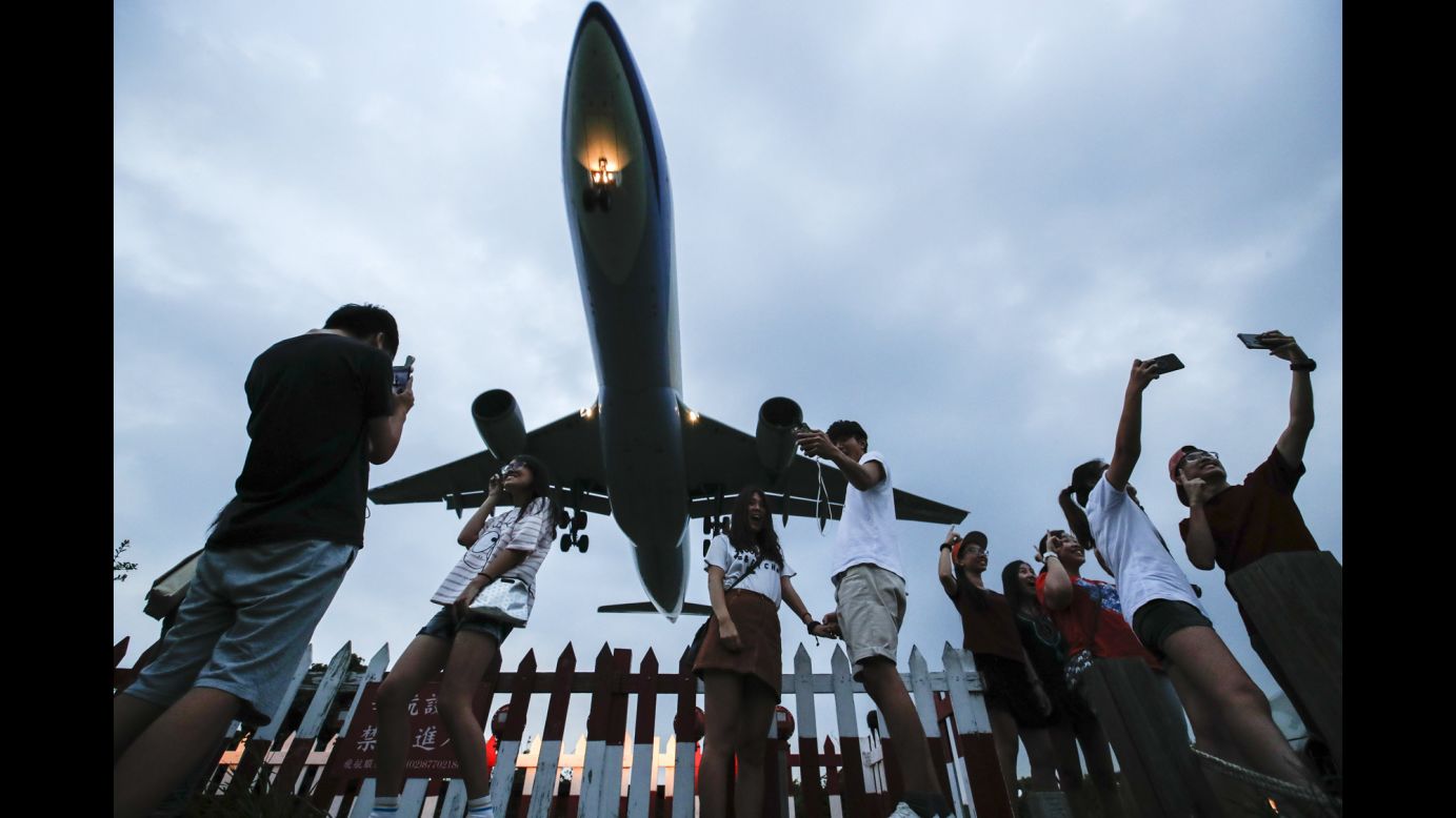 People take photos of an approaching passenger plane in Taipei, Taiwan, on Wednesday, September 6.
