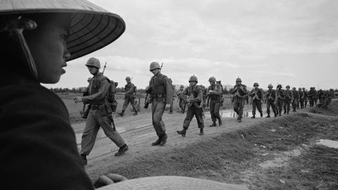 A Vietnamese woman watches U.S. Marines march toward defense positions in 1965. (AP Photo)