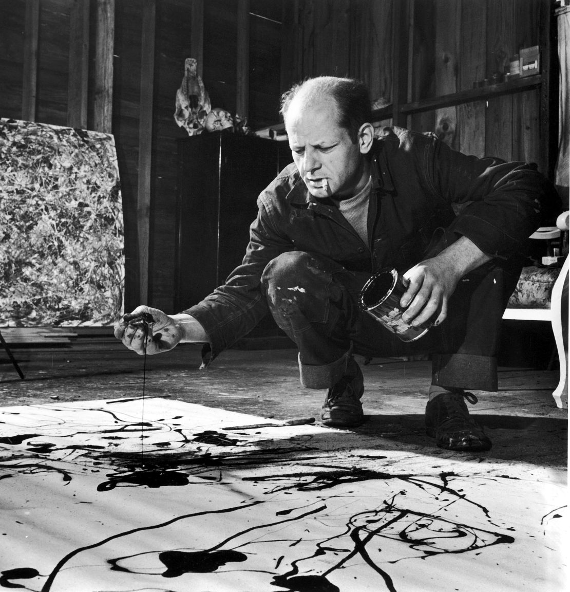 Jackson Pollock, cigarette in mouth, drops paint onto canvas.