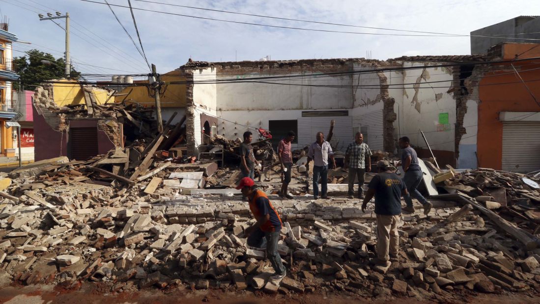 People stand on a building's rubble in Juchitan on September 8.