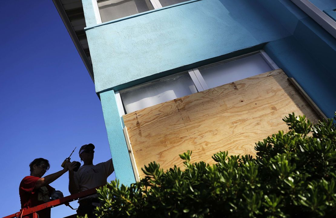 Paulita Kundid, left, and her brother Mike board up their apartment building on Friday in Daytona Beach.