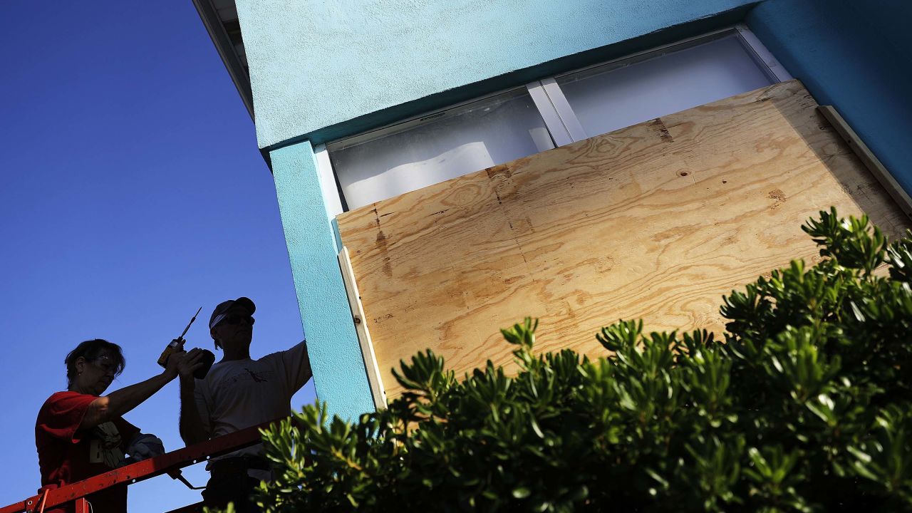 Paulita Kundid, left, and her brother Mike board up their apartment building on Friday in Daytona Beach.