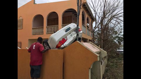 A man looks at a vehicle turned upside down in the British territory of Anguilla. 