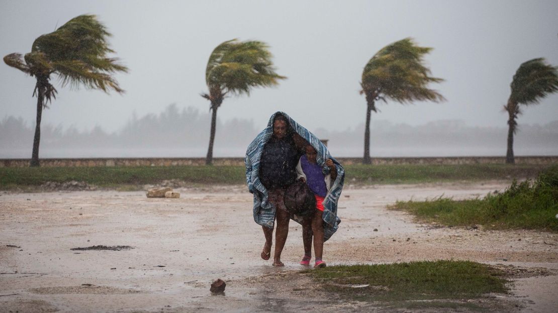 A woman and child use a blanket as protection from wind and rain as they walk Friday in Caibarien, Cuba.