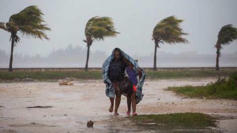 A woman and child use a blanket as protection from wind and rain as they walk Friday in Caibarien, Cuba.