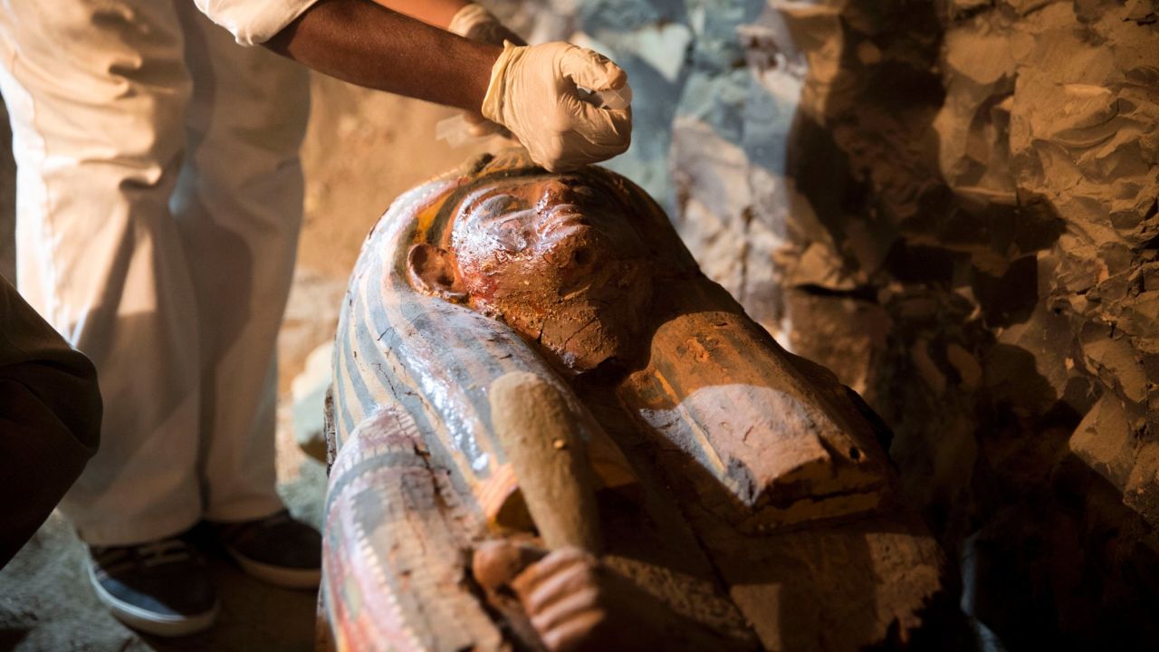 Workers inject glue into a coffin to protect the delicate old wood.