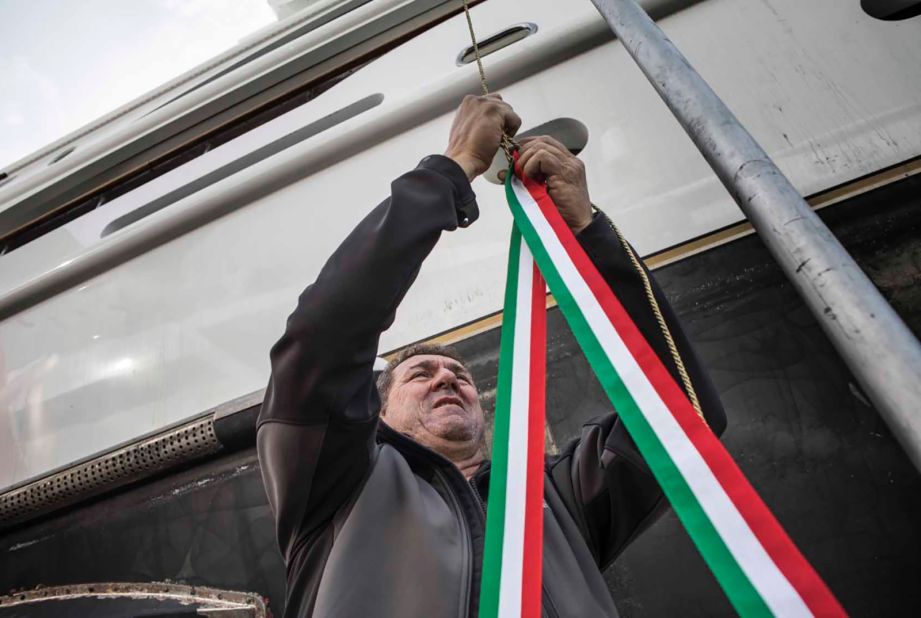 A shipyard employee secures ribbons in the colors of the Italian flagged that will aid in the traditional smashing of a champagne bottle against the Aurora's hull during the launch ceremony.