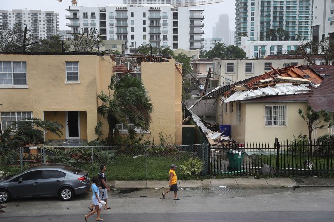 People walk past a building in Miami where the roof was blown off by Hurricane Irma on September 10.
