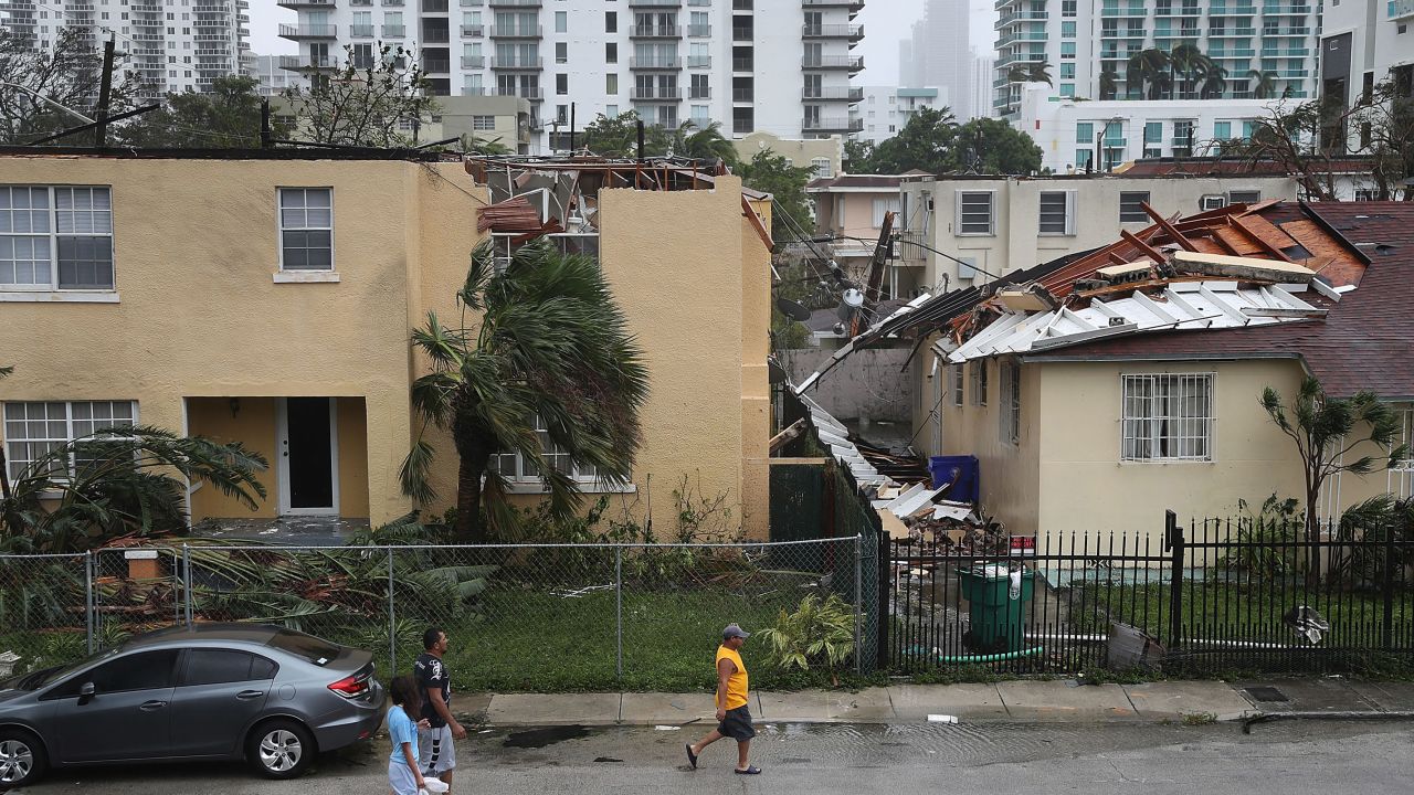 People walk past a building where the roof was blown off by Hurricane Irma in Miami.