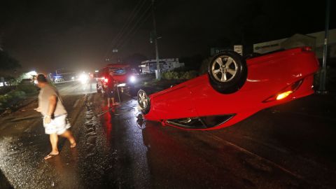 People in Cape Coral, Florida, tend to a car that flipped over during Hurricane Irma on Sunday, September 10.